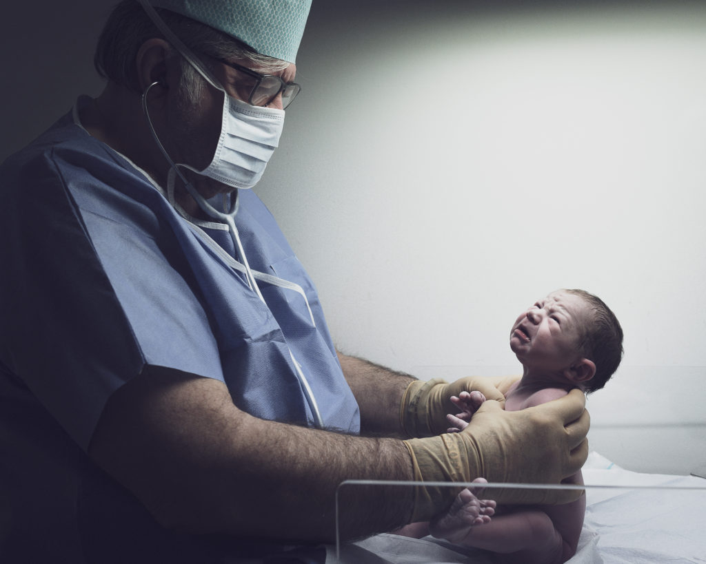 Nouveau né pleurant face à un pediatre puissant 