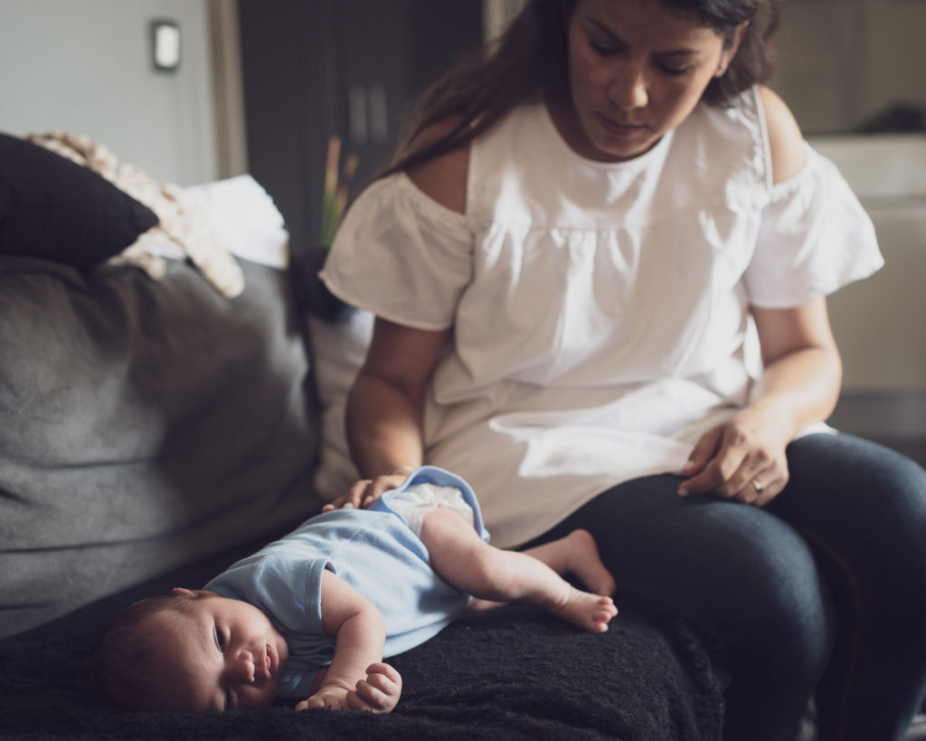 Mere prenant soin de son bebe allonge sur un canapé